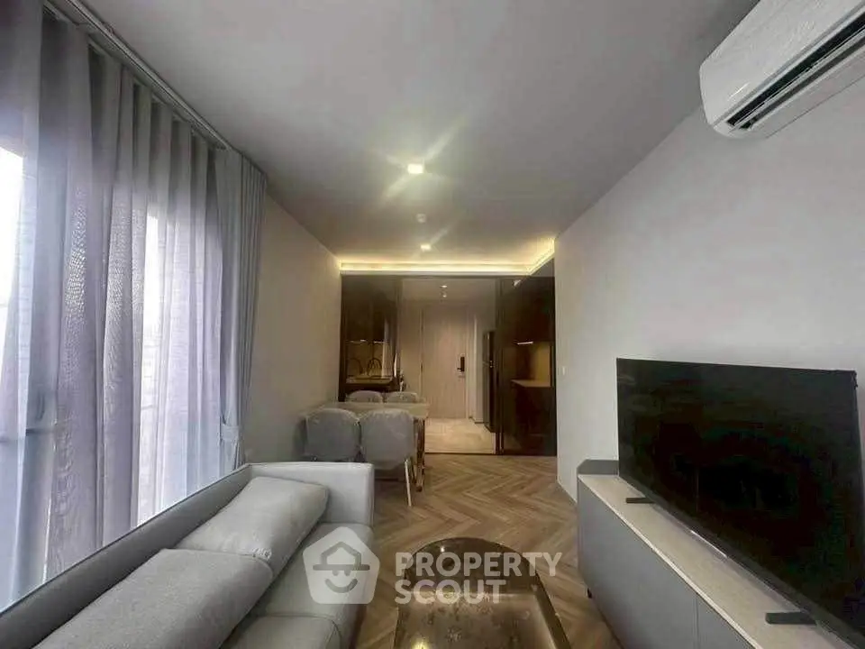 Modern living room with sleek design, featuring a cozy sofa, flat-screen TV, and elegant dining area.