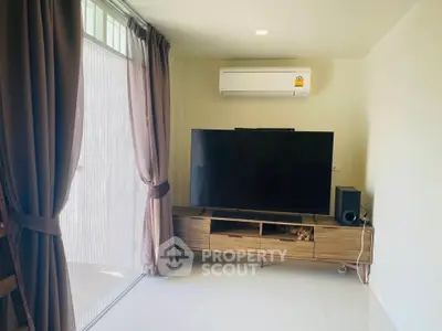 Modern living room with large TV and air conditioning, featuring elegant curtains and sleek furniture.