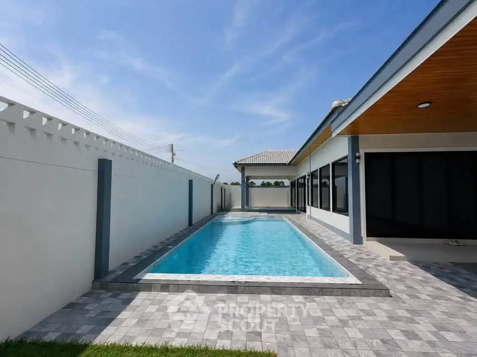 Luxurious modern home with private swimming pool and spacious patio area under clear blue skies.