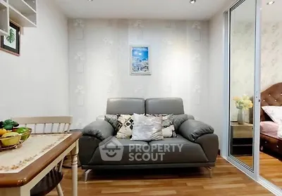 Cozy living room with modern sofa and dining area, adjacent to a stylish bedroom.