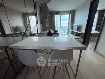 Modern apartment interior with dining area and city view, featuring sleek furniture and large windows.