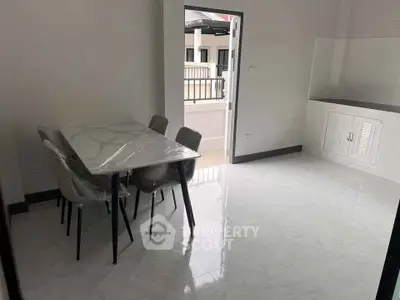 Spacious dining area with modern table and chairs, opening to a balcony with natural light.