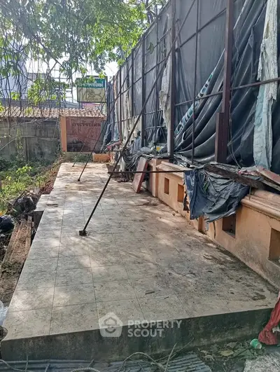 Outdoor construction site with tiled flooring and temporary fencing, potential for renovation or development.