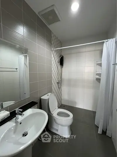 Modern bathroom with sleek fixtures and shower area in contemporary apartment.