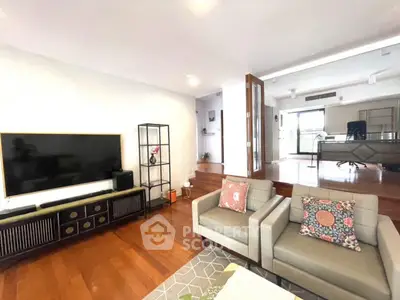 Spacious living room with modern decor and large TV, featuring hardwood floors and stylish furniture.