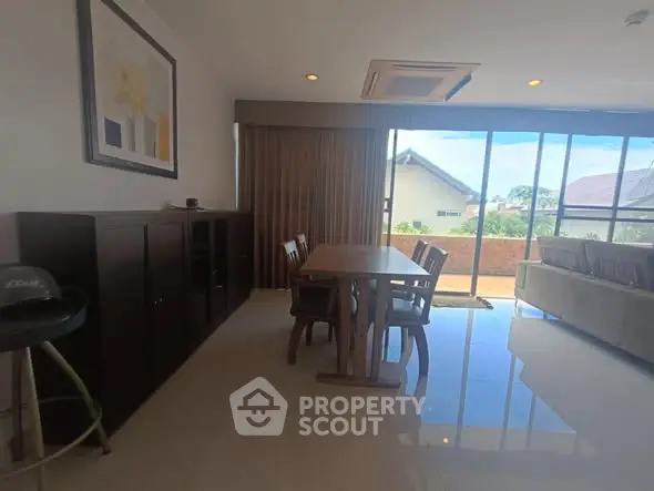 Spacious living room with large windows and elegant dining area