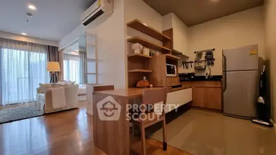 Modern open-layout kitchen and living room with wooden furniture and natural light.