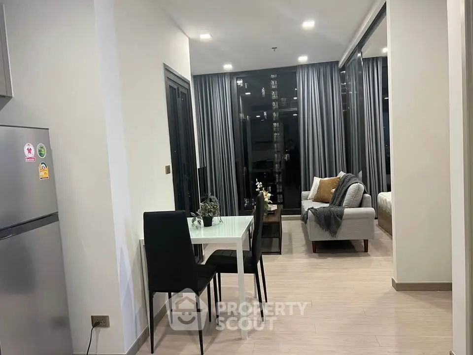 Modern open-plan living and dining area with sleek furniture and floor-to-ceiling windows.