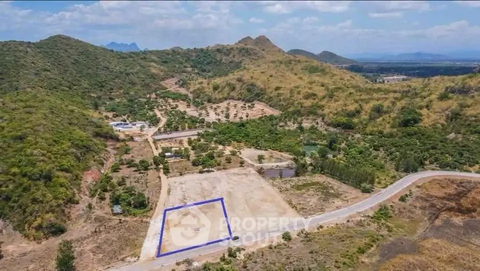 Scenic land plot with mountain views, ideal for development or investment, surrounded by lush greenery and clear skies.