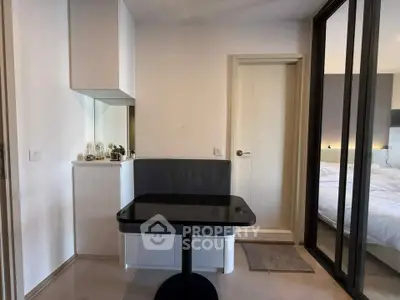 Modern compact dining area with sleek black table and cozy seating, adjacent to a stylish bedroom.