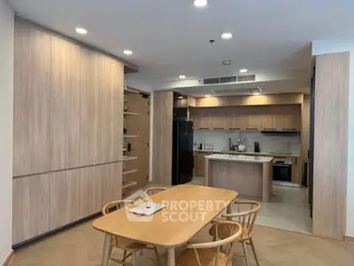 Modern kitchen with open layout and dining area featuring wooden cabinetry and sleek design.
