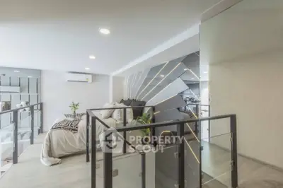 Modern loft interior with stylish decor and glass railing, featuring a cozy living area and sleek design elements.