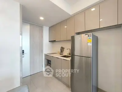Modern kitchen with sleek cabinetry and stainless steel fridge in a compact layout.