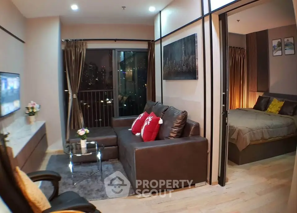 Modern living room with cozy seating and city view, adjacent to a stylish bedroom.