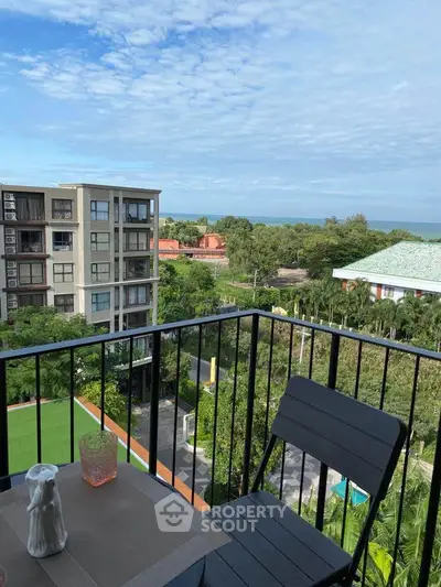 Charming balcony with scenic view of lush greenery and distant ocean, perfect for relaxation.