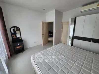 Spacious bedroom with large window and modern furniture, perfect for relaxation.