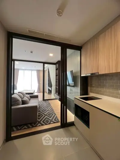 Modern open-layout kitchen leading to a stylish living room with natural light and contemporary decor.