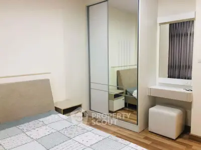 Cozy bedroom with mirrored wardrobe and wooden flooring in modern apartment.