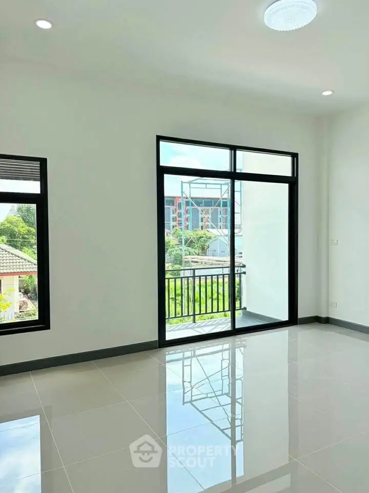 Bright and spacious living room with large windows and balcony access, offering a serene view.