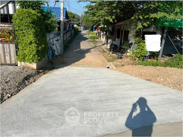 Charming residential street with newly paved road and lush greenery, ideal for peaceful living.