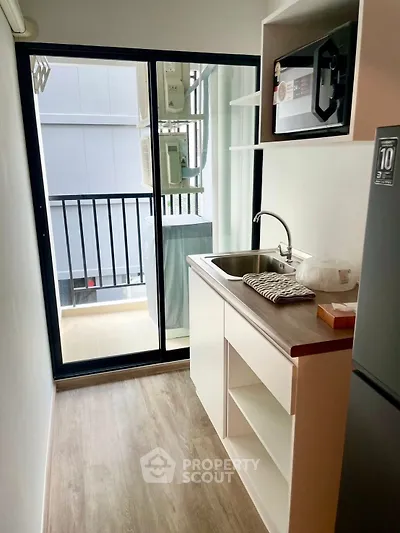 Compact kitchen with balcony access, featuring modern appliances and sleek design.