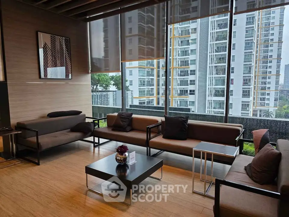 Modern living room with large windows and city view, featuring stylish furniture and wooden flooring.