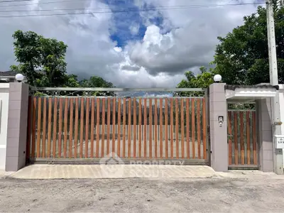 Elegant gated entrance with modern design and lush greenery, perfect for a luxurious property.