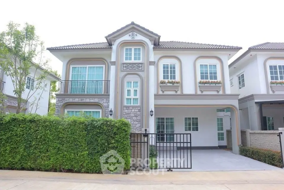 Elegant two-story house with gated driveway and lush greenery in a serene neighborhood.