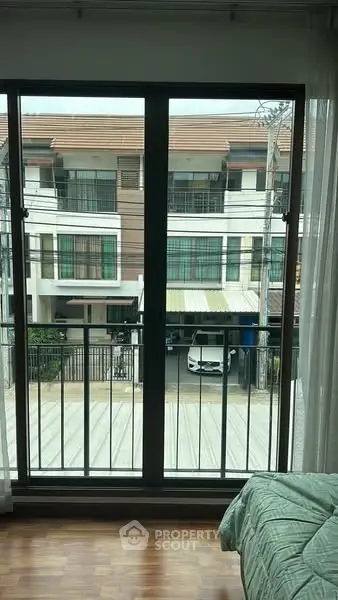 Modern bedroom with balcony view of contemporary townhouses