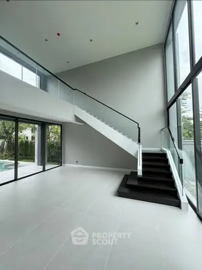 Spacious modern living room with high ceilings and large windows overlooking a garden.