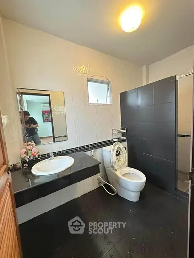 Modern bathroom with sleek black and white design, featuring a washing machine and stylish fixtures.