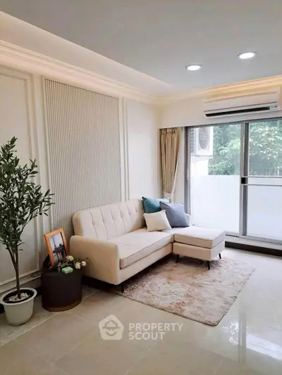 Elegant living room with modern sofa, large window, and stylish decor in a bright apartment.