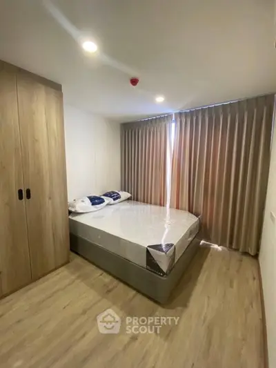 Modern bedroom with wooden flooring, large wardrobe, and cozy bed with natural light.