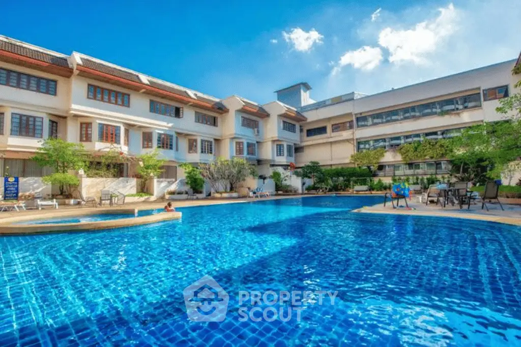 Luxurious residential complex with a stunning outdoor pool and modern architecture under a clear blue sky.
