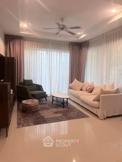 Elegant living room with plush sofas, large windows, and stylish decor in a modern home.