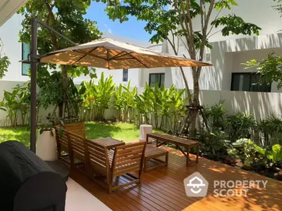 Charming garden patio with wooden deck and umbrella, perfect for outdoor relaxation.