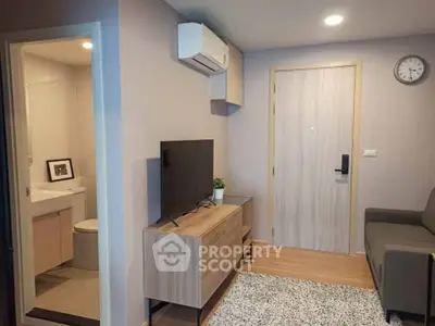 Modern living room with TV, air conditioning, and adjacent bathroom in cozy apartment.