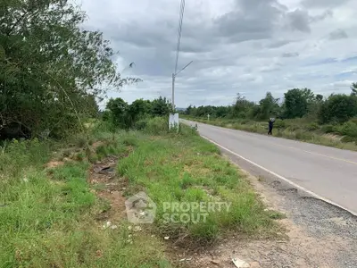 Scenic roadside land plot with lush greenery and open sky, ideal for development opportunities.