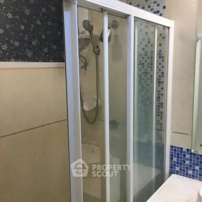Modern bathroom with glass shower enclosure and stylish blue mosaic tiles.