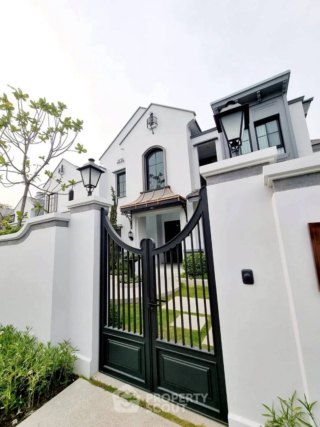 Elegant white house with black gate and lush greenery