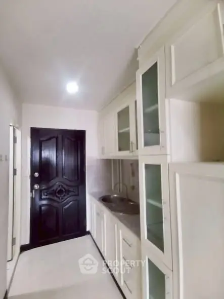 Compact kitchen with white cabinets and sleek black door