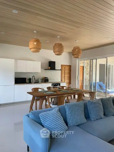 Modern open-plan living room with stylish kitchen and dining area, featuring elegant lighting and cozy seating.