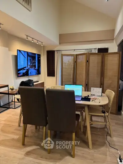 Spacious living room with modern decor and dining area, featuring a wall-mounted TV and stylish furniture.