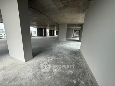 Spacious open-plan commercial space with concrete floors and large windows offering ample natural light.