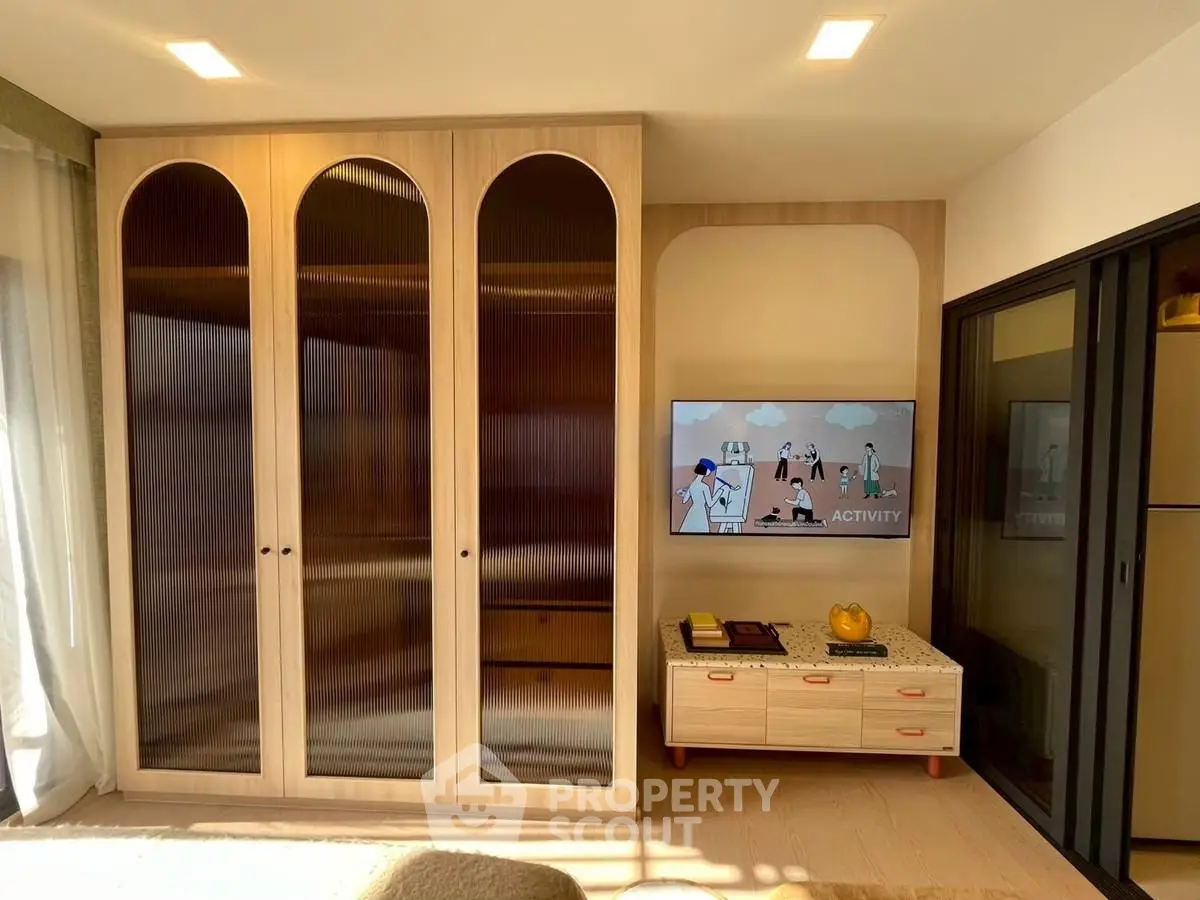 Modern living room with stylish wooden cabinets and mounted TV, featuring sleek design and warm lighting.