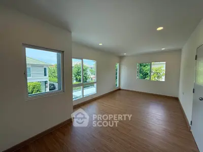 Spacious empty room with large windows and wooden flooring, perfect for customization.