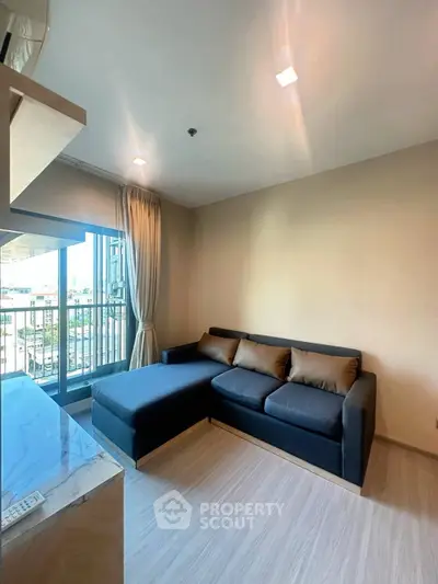 Modern living room with stylish sofa and large window offering natural light and city view.