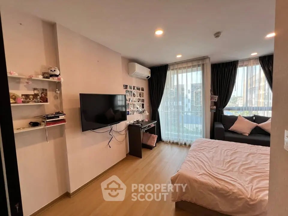 Cozy bedroom with modern decor, featuring a wall-mounted TV, air conditioning, and a large window with city view.