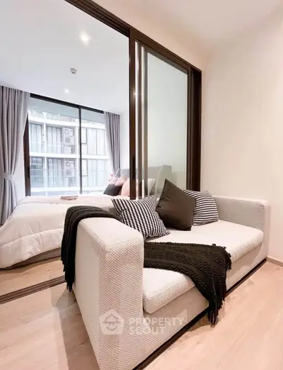 Modern bedroom with cozy sofa and large window in stylish apartment