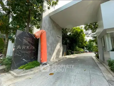Modern building entrance with sleek design and lush greenery, ideal for urban living.